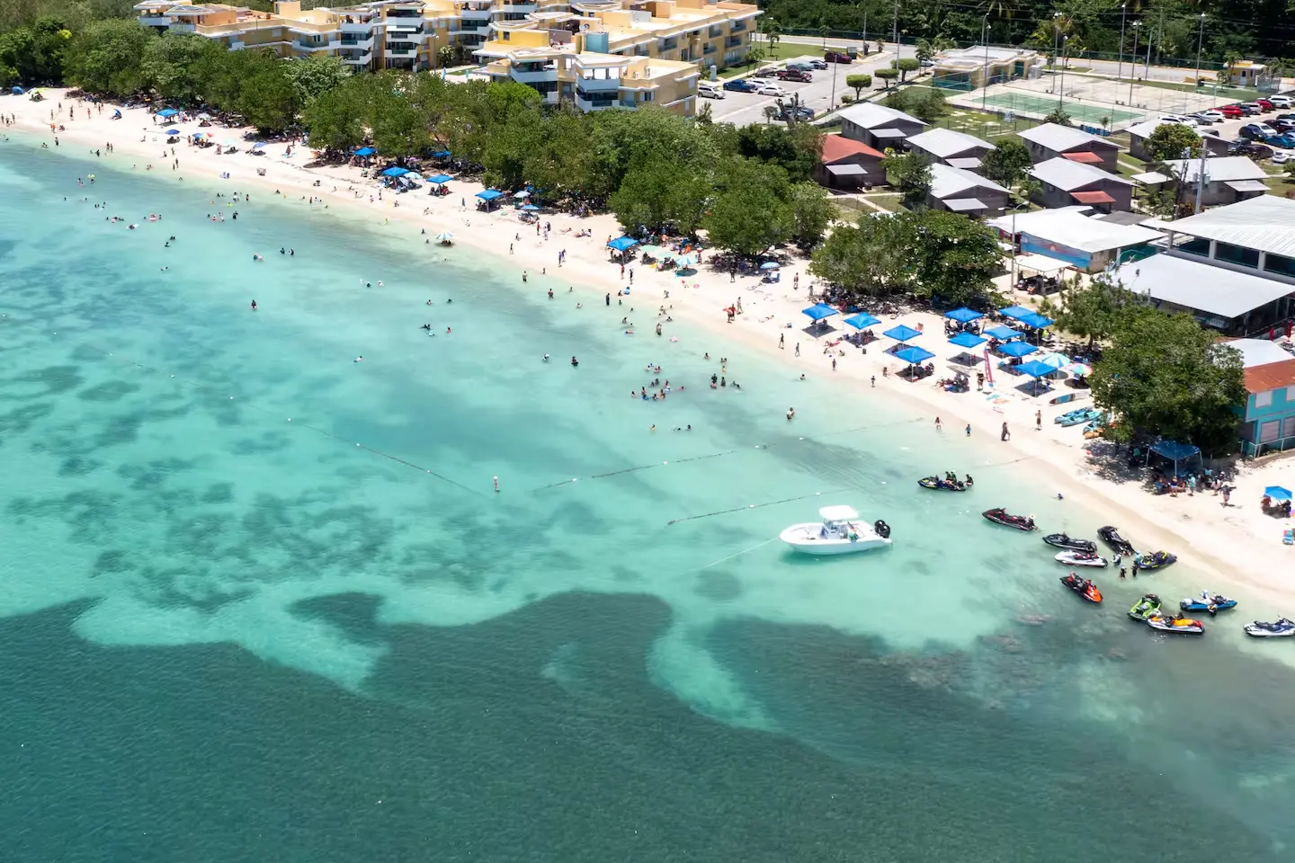 Aerial view of Playa Buyé with turquoise water, beachgoers and boats